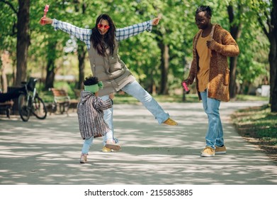 Happy Diverse Family Of Three Spending Their Free Time In The Park And Enjoying Beautiful Sunny Day Outside. Multiracial Parents And Their Cute Little Daughter Having Fun Together.