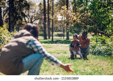 Happy Diverse Family Of Three Spending Their Free Time In The Park And Enjoying Beautiful Sunny Day Outside. Multiracial Parents And Their Cute Little Daughter Having Fun Together.