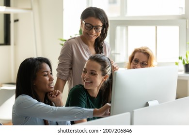 Happy diverse female business team meeting at desktop computer, watching presentation on monitor, talking about work tasks, smiling, laughing. Employee presenting project solution, showing content
