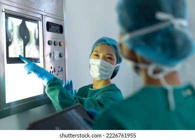 Happy, diverse female surgeons discussing x-ray on lightbox in operating theatre. Hospital, medical and healthcare services. - Powered by Shutterstock - Get 15% off with code: PIKWIZARD15