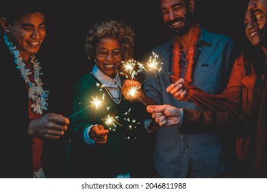 Happy diverse friends celebrating with sparklers on new year eve - Soft focus on african woman face