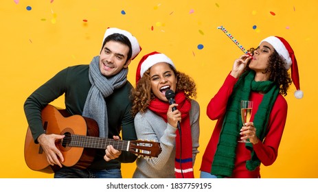 Happy diverse friends having party singing and celebrating Christmas in yellow studio background with colorful confetti - Powered by Shutterstock