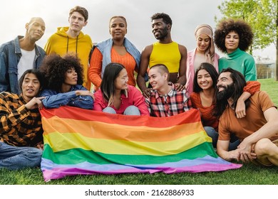 Happy diverse friends holding LGBT rainbow flag having fun together outdoors - Main focus on bald girl face - Diversity community concept - Powered by Shutterstock