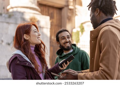 Happy diverse friends interacting outside. Multicultural group of young adults using smartphones and socializing in urban setting. Concept of friendship, diversity, and modern communication. - Powered by Shutterstock