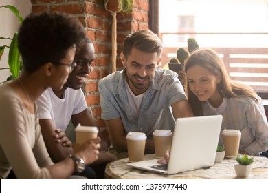 Happy Diverse Friends Students Group Looking At Laptop Having Fun Watching Comedy Movie, Online Show, Funny Video, Multiracial Young People Laughing Together Using Computer In Coffee House