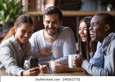 Happy diverse friends taking group selfie on cellphone in cafe, cheerful multiracial students making photo using snapshot app watching funny video on smartphone sitting at coffee shop table together - Powered by Shutterstock