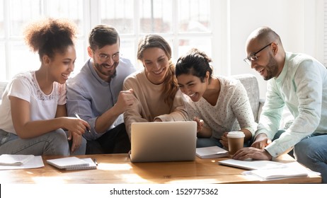 Happy Diverse Friends Watching Funny Video, Laughing At Joke, Using Laptop, Having Fun Together, Sitting On Couch, Looking At Computer Screen, Students Colleagues Working On Online Project