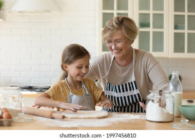 Happy diverse generations female family having fun, involved in preparing homemade pastry together in modern kitchen. Joyful old granny sharing culinary skills with cute little granddaughter. - Shutterstock ID 1997456810