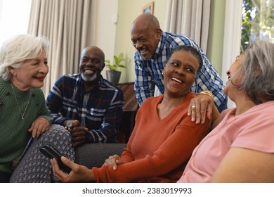 Happy diverse group of senior friends having video call and discussing in sunny living room. Retirement, friendship, domestic life and senior lifestyle, communication, technology, unaltered. - Powered by Shutterstock