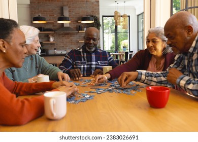 Happy diverse group of senior friends playing with jigsaw puzzles in sunny dining room at home. Retirement, friendship, wellbeing, activities, togetherness and senior lifestyle, unaltered. - Powered by Shutterstock