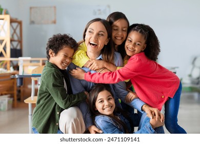 Happy diverse kids, junior school children embracing female teacher appreciating and thanking educator in classroom - Powered by Shutterstock