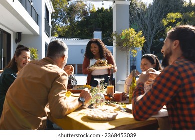 Happy diverse male and female friends serving thanksgiving celebration meal in sunny garden. Celebration, friendship, patriotism, american culture and tradition, unaltered. - Powered by Shutterstock