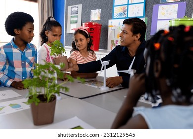 Happy diverse male teacher and children in elementary school class with windmills and plants. School, ecology and education, unaltered. - Powered by Shutterstock