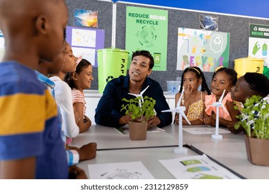 Happy diverse male teacher and children in elementary school class with windmills and plants. School, ecology, childhood, learning and education, unaltered. - Powered by Shutterstock