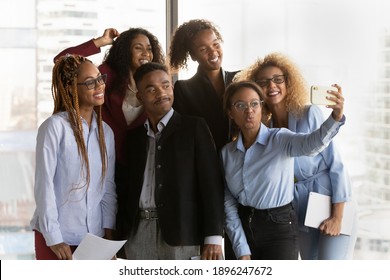 Happy diverse multiethnic colleagues have fun make self-portrait picture on cellphone together. Smiling young multiracial businesspeople pose for selfie on smartphone in office. Technology concept. - Shutterstock ID 1896247672