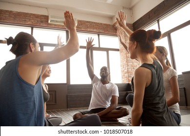 Happy diverse people raise hands together feel emotional motivated after yoga training sitting on mats in studio, excited black and white friends celebrate unity support each other at group seminar - Powered by Shutterstock