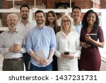 Happy diverse professional business team stand in office looking at camera, smiling young and old multiracial workers staff group pose together as human resource, corporate equality concept, portrait