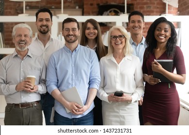 Happy Diverse Professional Business Team Stand In Office Looking At Camera, Smiling Young And Old Multiracial Workers Staff Group Pose Together As Human Resource, Corporate Equality Concept, Portrait