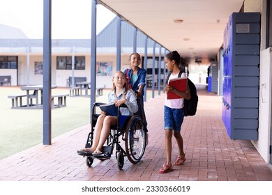 Happy diverse schoolgirl in wheelchair with her friends in corridor at school. Education, inclusivity, school, learning and disability concept. - Powered by Shutterstock