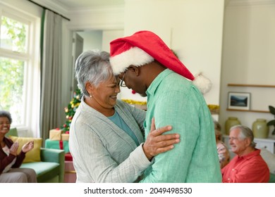 Happy diverse senior couple dancing in front of their diverse friends at christmas time. christmas festivities, celebrating at home with friends. - Powered by Shutterstock