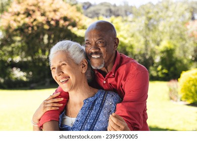 Happy diverse senior couple embracing in sunny garden. Lifestyle, retirement, senior lifestyle, nature, togetherness and domestic life, unaltered. - Powered by Shutterstock