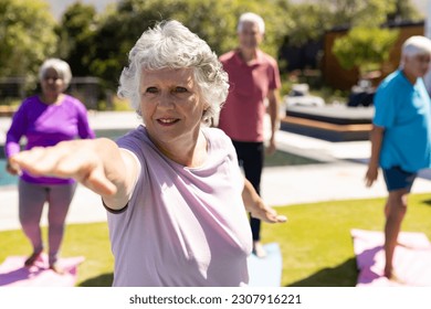 Happy diverse senior friends practicing yoga standing in sunny garden. Senior lifestyle, active retirement, friendship, health and wellbeing, unaltered. - Powered by Shutterstock