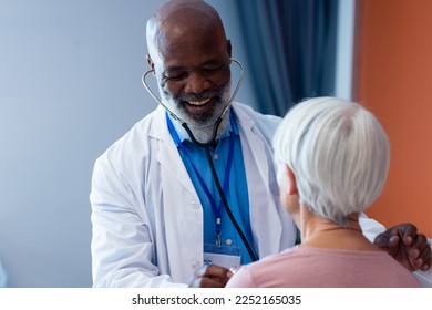 Happy diverse senior male doctor using stethoscope on senior female patient, copy space. Hospital, medical and healthcare services. - Powered by Shutterstock