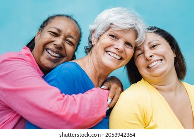 Happy diverse senior people hugging each other outdoor - Older friends community concept - Focus on center woman face
