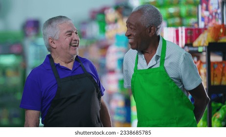 Happy diverse senior workers standing at grocery store smiling at camera wearing uniforms. Older Brazilian staff workers - Powered by Shutterstock