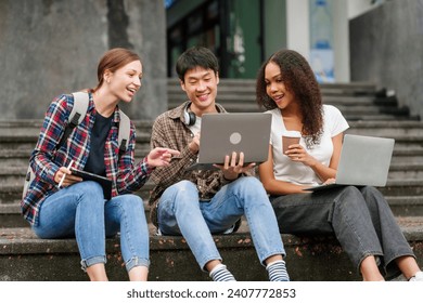 Happy diverse university students sitting on steps, using laptops and tablets, enjoying conversation. Student exchange and study abroad program, Asian man, african american woman and caucasian people. - Powered by Shutterstock