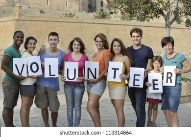 happy and diverse volunteer group holding sign