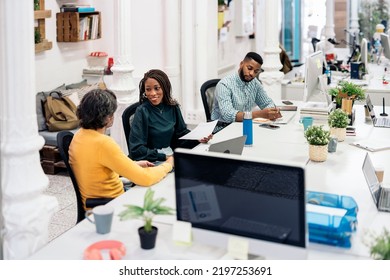 Happy Diverse Work Team Sitting In Big Desk And Doing Paper Work. Co-working Concept.