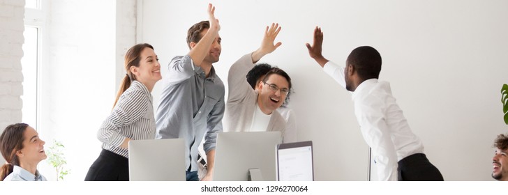 Happy diverse workmates giving high five celebrating corporate success feels excited in workplace, succeed common goal career growth concept, banner for website header design with copy space for text - Shutterstock ID 1296270064