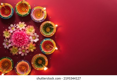 Happy Diwali - Clay Diya lamps lit during Diwali, Hindu festival of lights celebration. Colorful traditional oil lamp diya on red background - Shutterstock ID 2195344127