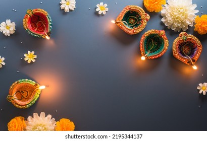 Happy Diwali - Clay Diya lamps lit during Diwali, Hindu festival of lights celebration. Colorful traditional oil lamp diya on blue background - Shutterstock ID 2195344137