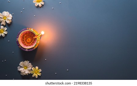 Happy Diwali - Clay Diya lamps lit during Diwali, Hindu festival of lights celebration. Colorful traditional oil lamp diya on blue background - Shutterstock ID 2198338135