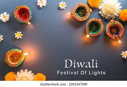 Happy Diwali - Clay Diya lamps lit during Diwali, Hindu festival of lights celebration. Colorful traditional oil lamp diya on blue background - Shutterstock ID 2201547589