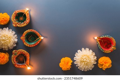 Happy Diwali - Clay Diya lamps lit during Diwali, Hindu festival of lights celebration. Colorful traditional oil lamp diya on blue background