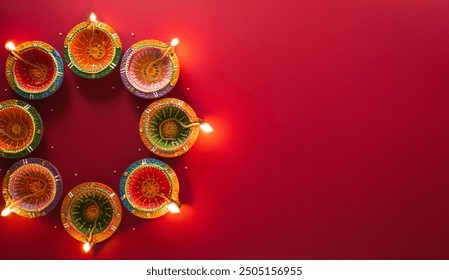 Happy Diwali - Clay Diya lamps lit during Diwali, Hindu festival of lights celebration. Colorful traditional oil lamp diya on red background - Powered by Shutterstock