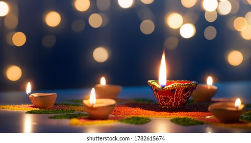 Happy Diwali, Diya lamps lit on colorful rangoli with bokeh light background