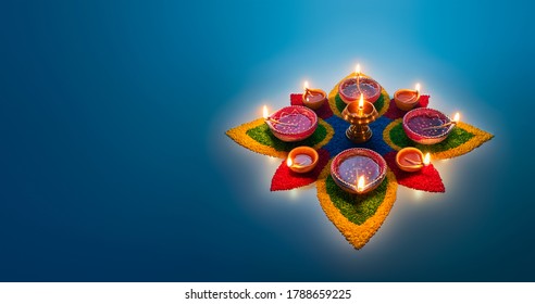 Happy Diwali, diya lamps lit on colorful rangoli