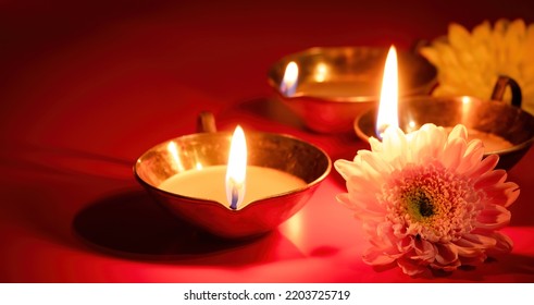 Happy Diwali. Diya oil lamp and flowers on red background. Traditional Hindu celebration. Religious holiday of light. Copy space, banner format. - Powered by Shutterstock