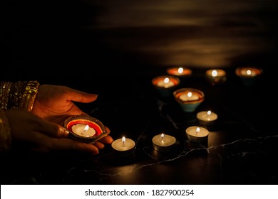 Happy Diwali - Woman Hands With Henna Holding Lit Candle Isolated On Dark Background. Clay Diya Lamps Lit During Dipavali, Hindu Festival Of Lights Celebration. Copy Space For Text.