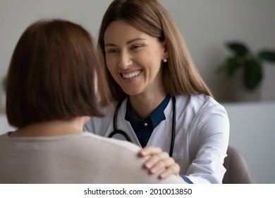 Happy Doctor Giving Support To Elder Patient, Touching Shoulder, Congratulating On Recovery And Good Medical Examination Result. Physician Talking To Retiree With Optimistic Smile, Telling Good News