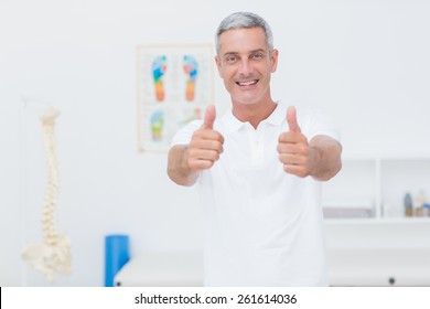 Happy doctor looking at camera with thumbs up in medical office - Powered by Shutterstock