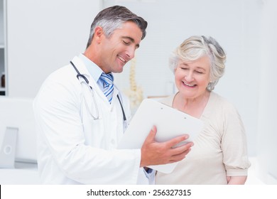 Happy Doctor And Patient Discussing Over Reports In Clinic