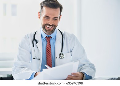 Happy doctor reading medical documentation - Powered by Shutterstock