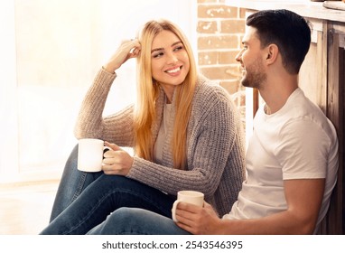 Happy domestic moments. Man and woman sitting on floor in sunlit kitchen, blank space - Powered by Shutterstock