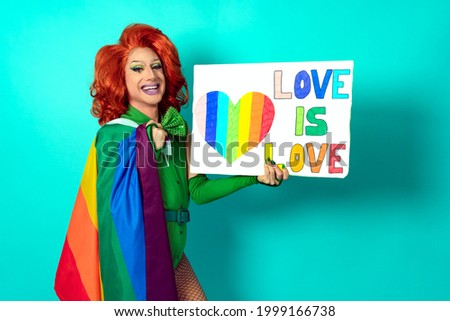 Happy drag queen celebrating gay pride holding banner with rainbow flag symbol of LGBTQ community - Focus on banner
