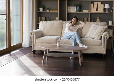 Happy Dreamy Latin Girl Relaxing On Home Couch, Looking At Window Away, Planning Good Events, Weekends, Smiling At Thoughts. Young Homeowner Woman Resting On Sofa In Living Room, Enjoying Leisure